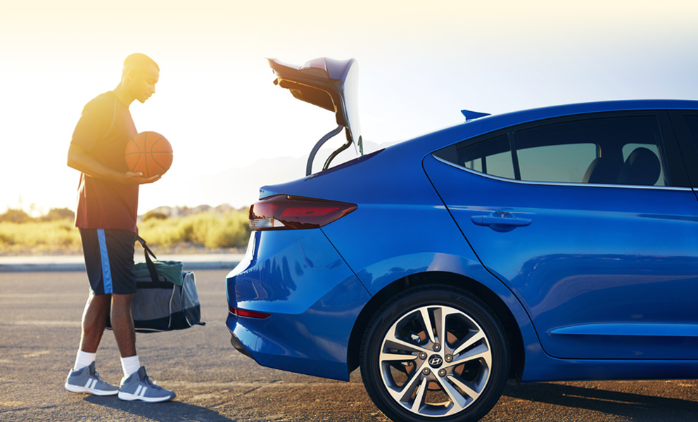 Man in athletic gear putting his duffel bag into the back of a Hyundai